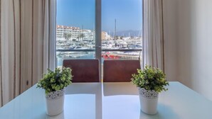 A room with a view of a marina, two potted plants on a table, and a window with curtains. - Del Port by Interhome (Empuriabrava)