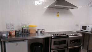 Una cocina equipada con estufa, horno, microondas y un bote de basura.