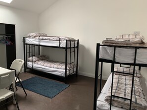 Una habitació de dormitori amb literes, un escriptori, una cadira i un tapet blau.