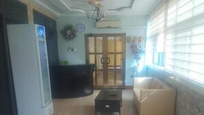 Amplia sala de estar con ventilador de techo, un sofá, una mesa de centro y un refrigerador.