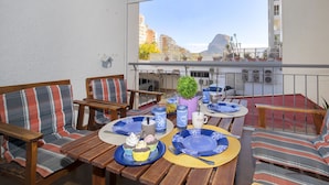 A balcony with wooden furniture, a table set with plates, cups, and a potted plant. - Europa I by Interhome (Calpe/Calp)