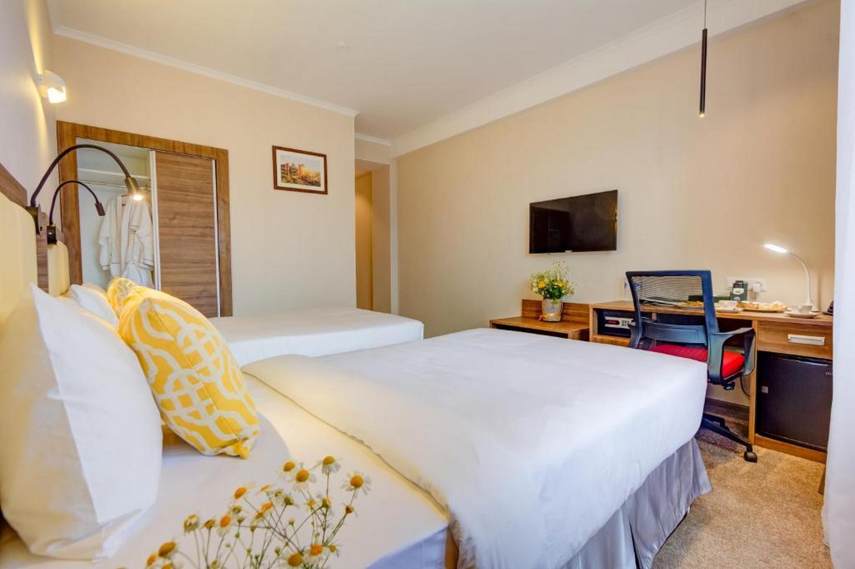 A hotel room with a bed, a desk, a chair, a TV, and a wardrobe.