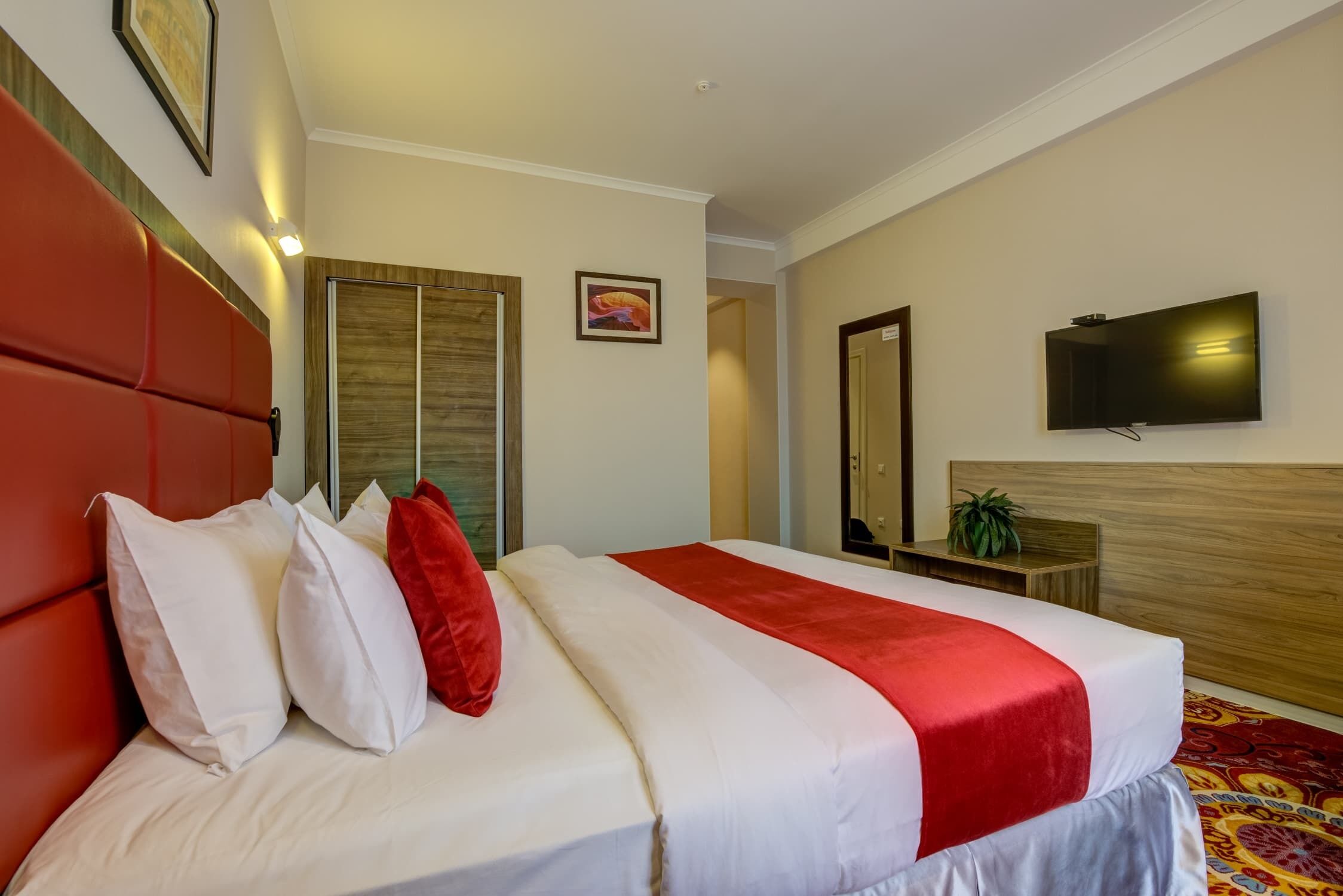 Une chambre d’hôtel avec un grand lit, une télévision et un miroir.