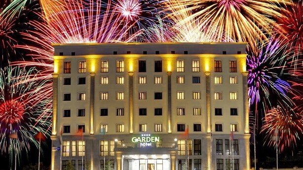 A hotel with a central entrance, multiple floors, and a well-lit facade. - Garden Hotel & Spa (Bishkek)