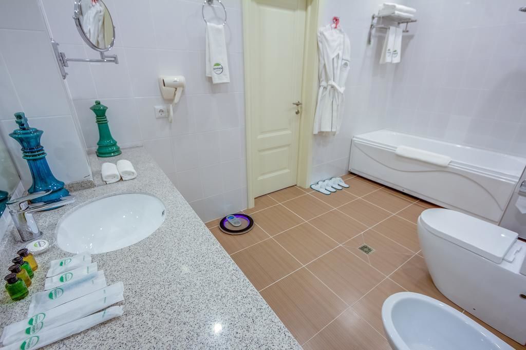 Une salle de bain équipée d’un lavabo, de toilettes et d’une baignoire. On y trouve des serviettes et des articles de toilette sur le comptoir.