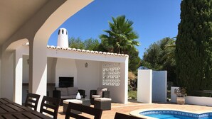 Eine Außenpatio mit Pool, Sitzbereich und Fernseher.