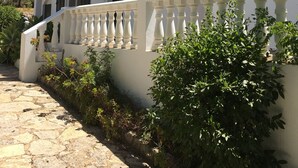 Ein weißes Gebäude mit Balkon, Steinweg und Grünflächen.