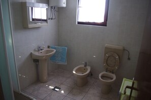 A bathroom with a sink, two toilets, and a window. - Apartments Antonia (Novalja)