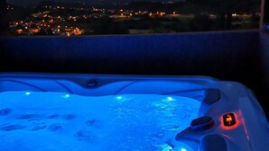 A hot tub with blue lighting, a control panel, and a view of a town at dusk. - Viksa with Hot Tub (Zagreb)
