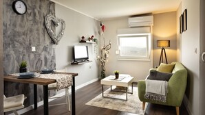A modern living room with a dining area, a green armchair, a small table with a lamp, and a heart-shaped decoration on the wall. - Viksa with Hot Tub (Zagreb)