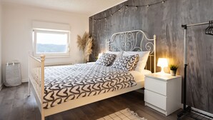 A bedroom with a bed, bedside table, lamp, and a window. - Viksa with Hot Tub (Zagreb)