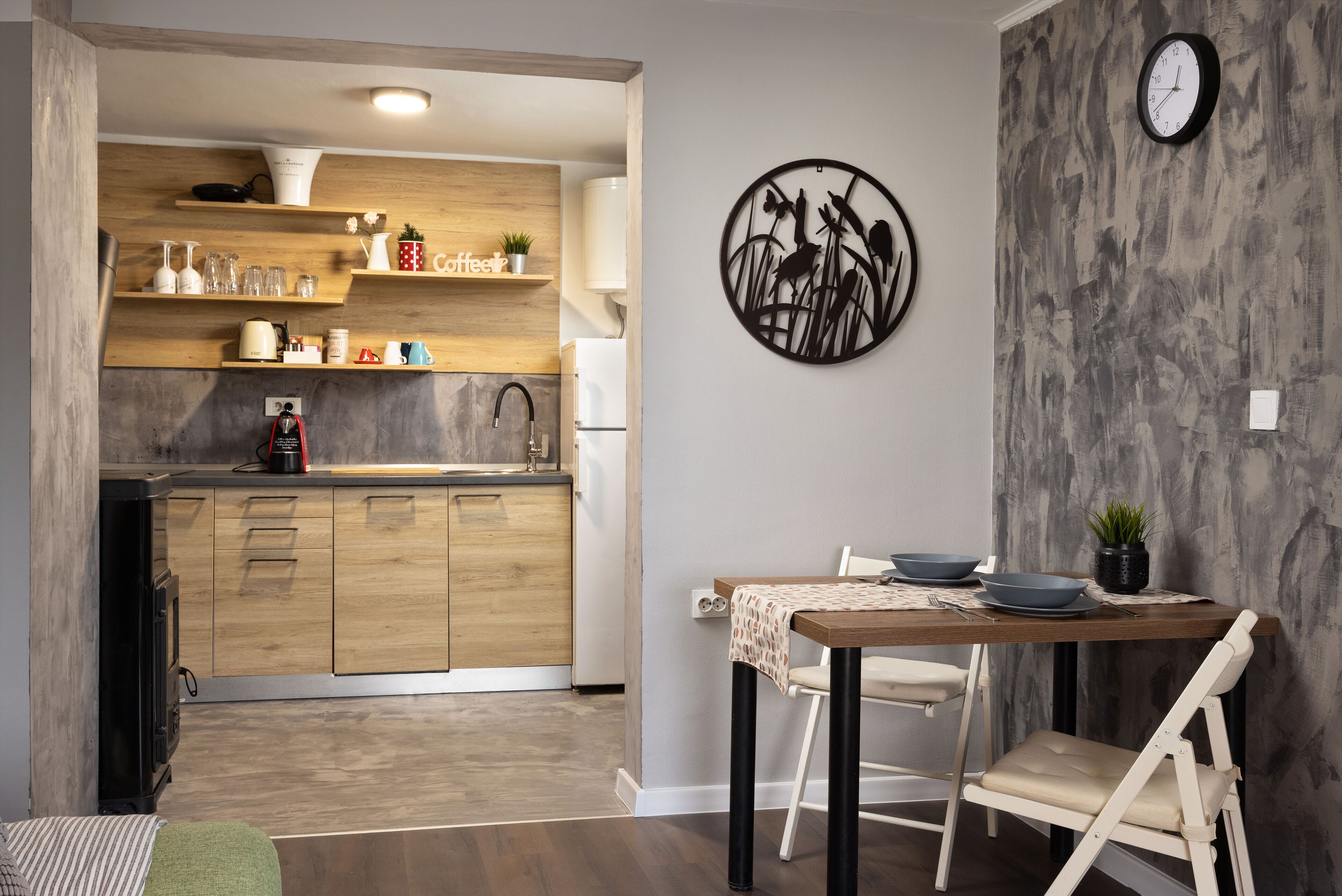 A modern kitchen with wooden cabinets, a built-in oven, and a coffee station.