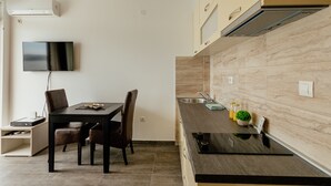 Une cuisine moderne avec un coin repas, un téléviseur à écran plat et un climatiseur intégré.