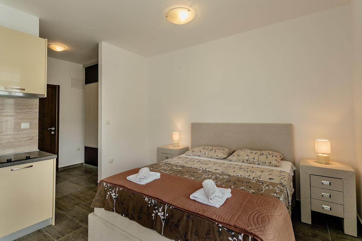 Una habitación de hotel con cama, mesitas de noche, escritorio y armario.
