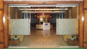A reception area with a glass door, wooden paneling, and a reception desk.