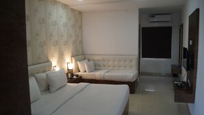 A hotel room with two beds, a TV, and an air conditioning unit.