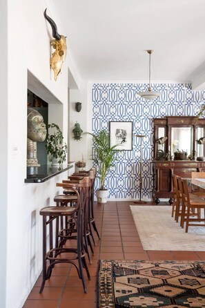 A dining area with a patterned wall, a wooden dining table, and chairs.