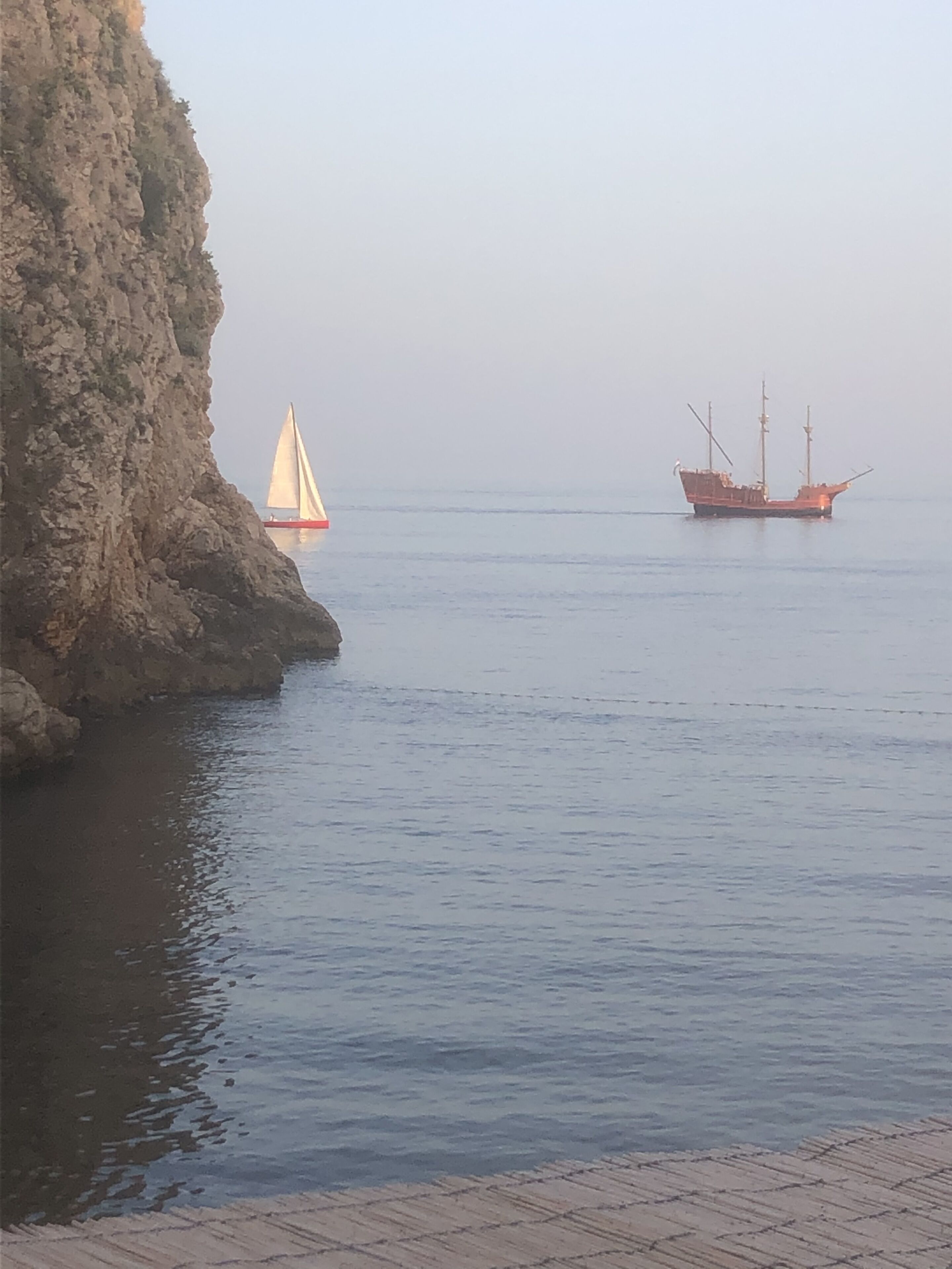 A coastal scene with a rocky cliff and calm sea.