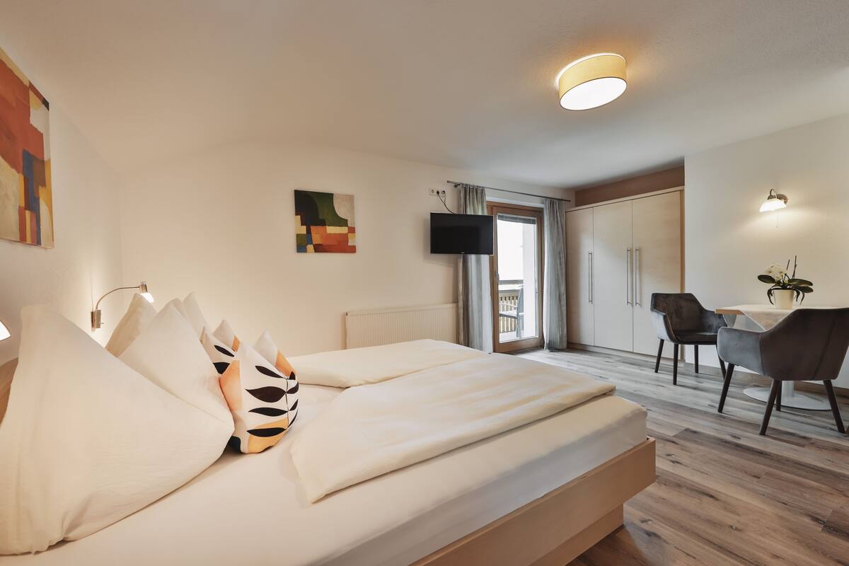 A modern hotel room with a large bed, a desk, and a TV.