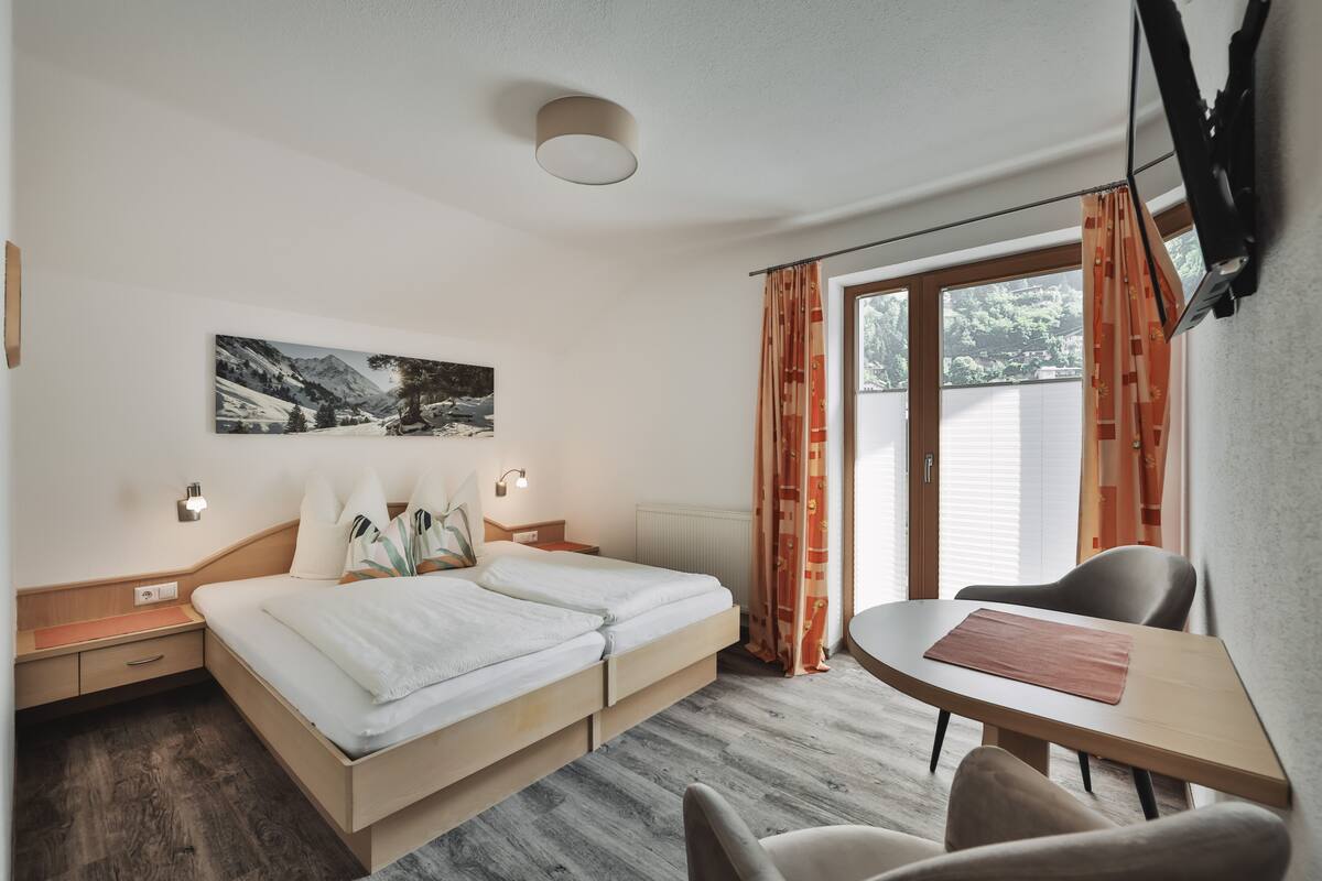 A hotel room with a bed, bedside tables, a desk, and a chair.