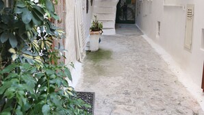 A narrow alleyway with a stone floor, a staircase leading to an upper level, and a door with a number sign. - Casa Ares Sperlongaresort (Sperlonga)
