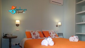 A hotel room with a bed, two pillows, a bedside table with a lamp, and a wall-mounted air conditioner. - Casa Ares Sperlongaresort (Sperlonga)