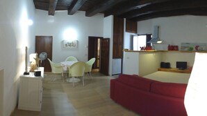 A compact living space with a dining area, a red sofa, and a kitchenette. - Casa Penelope Sperlongaresort (Sperlonga)