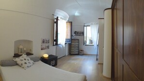 A narrow, well-lit room with a bed, bedside tables, a dresser, and a window with curtains. - Casa Penelope Sperlongaresort (Sperlonga)