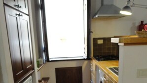A compact kitchen with a washing machine, a small window, and a red rug. - Casa Penelope Sperlongaresort (Sperlonga)