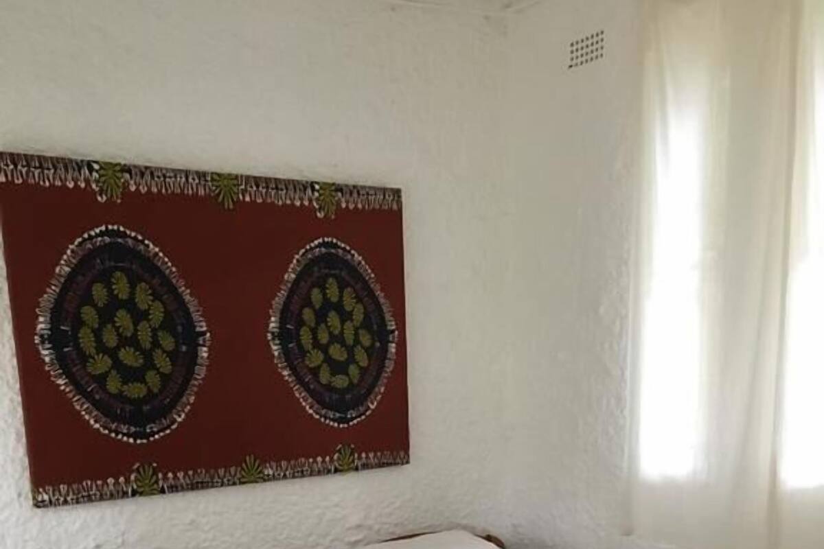 Une chambre avec deux lits en bois, du linge de lit blanc et une tapisserie murale.