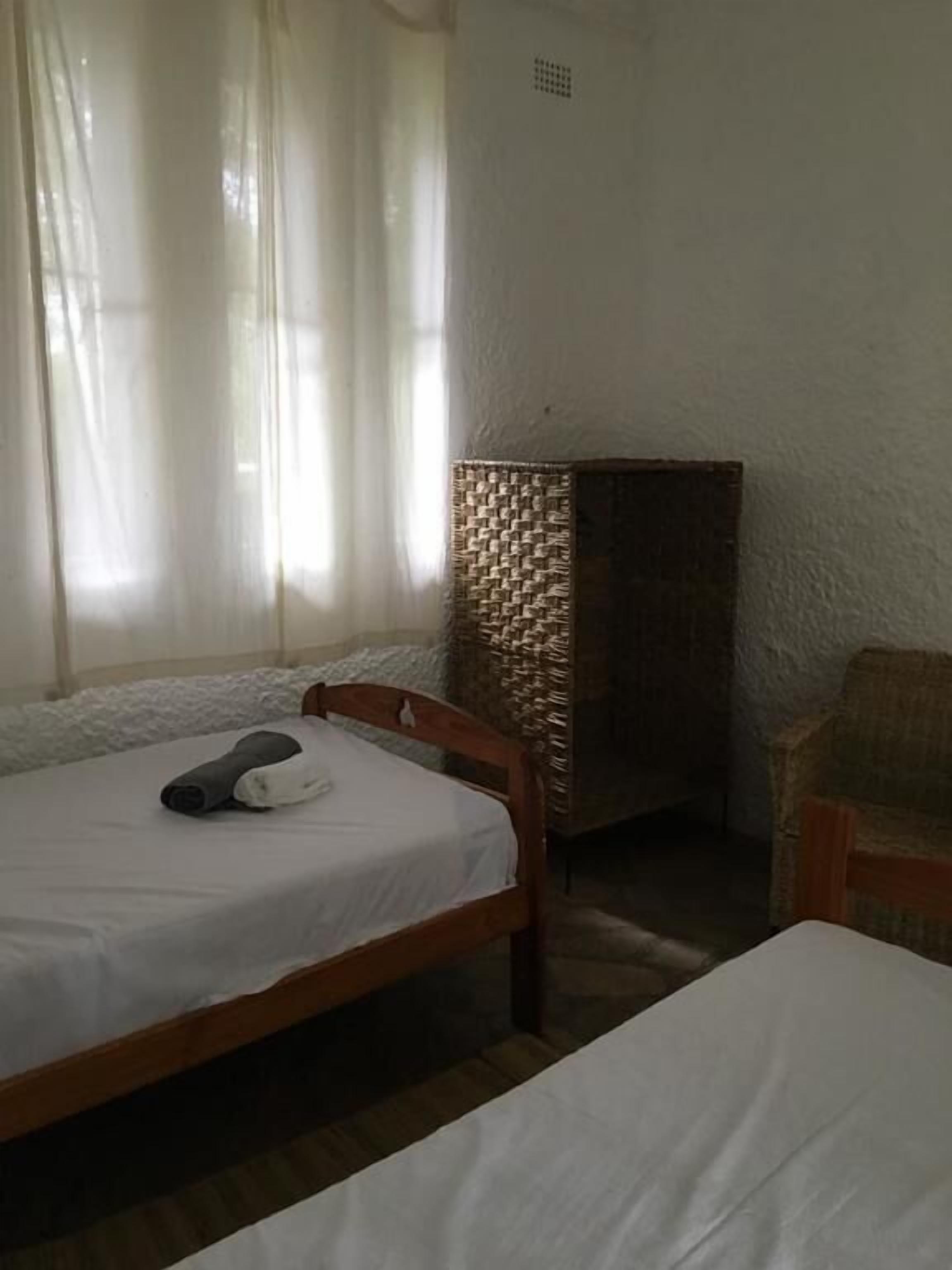 A room with a bed, a chair, and a woven basket against the wall.