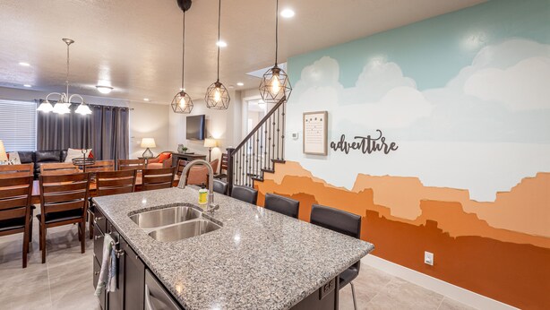A modern kitchen with granite countertops, a stainless steel sink, and pendant lighting.