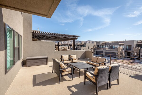 A rooftop patio with outdoor furniture, a pergola, and a view of the cityscape.