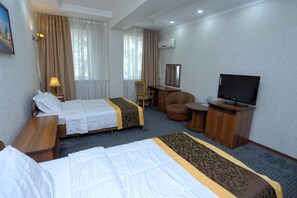 A hotel room with two beds, a desk, a chair, a television, and a wardrobe. - VIARDO Hotel (Tashkent)