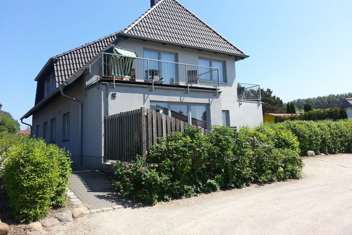 Une maison à deux étages avec un balcon, une cour clôturée et un ciel dégagé.