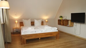 Ein Schlafzimmer mit einem hölzernen Bett, Nachttischlampen, einem Flachbildfernseher und einer kleinen Ablage für Toilettenartikel.