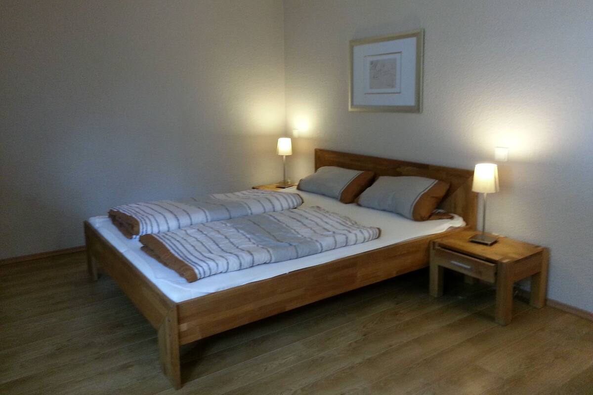A single bed with a wooden frame, two bedside tables, and a framed picture on the wall.