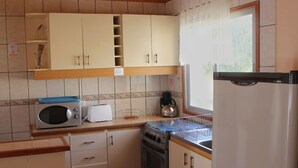 Eine kleine Küche mit weißen Schränken, einer Mikrowelle, einem Toaster und einem Wasserkocher.