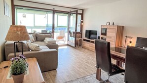 A modern living room with a sofa, a dining table with a plant, a TV, and a wooden cabinet. - Bergliebe (G 103) by Interhome (Dittishausen)