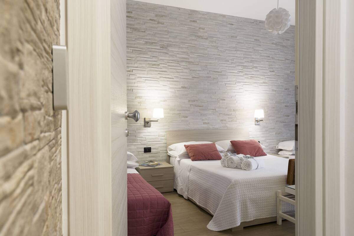 A bedroom with two beds, a stone wall, and a wooden floor.