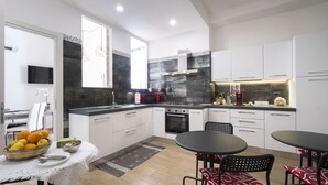 Una cocina moderna con armarios blancos, una encimera negra y un comedor con mesa y sillas.