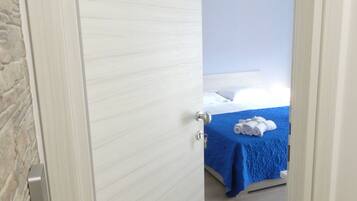 A hotel room with a bed, a blue bedspread, and a number '5' on the door.
