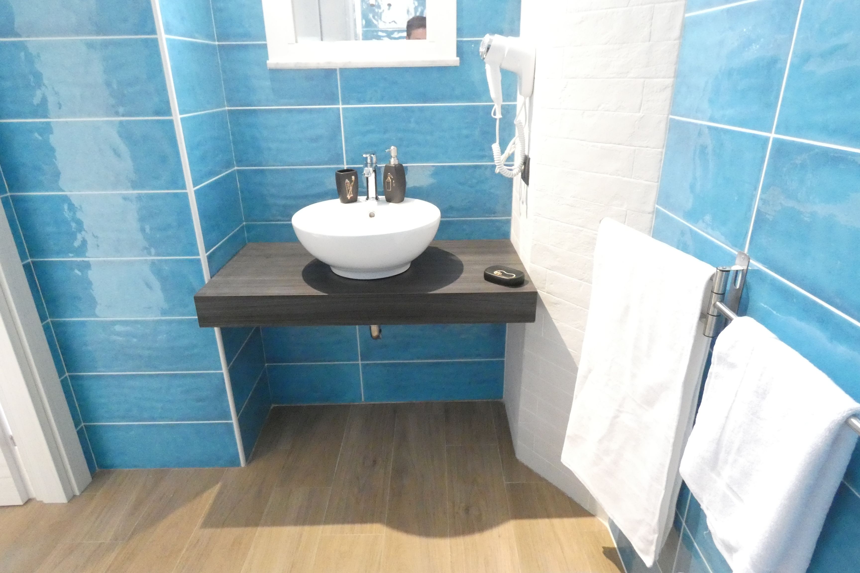 A bathroom with a white sink, blue tiles, and a towel rack.