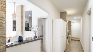 Una cocina moderna con una pared de acento de piedra, un refrigerador blanco y una encimera con utensilios de cocina.