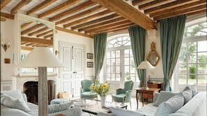 A room with a fireplace, a sofa, a table with a lamp, and a chair. - Le Domaine de Ravenoville (Sainte-Mere-Eglise)
