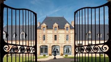 A large stone building with a symmetrical facade, multiple windows, and a central entrance.