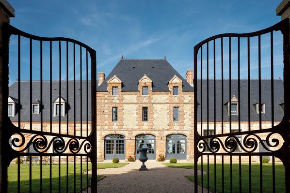 A large stone building with a symmetrical facade, multiple windows, and a central entrance.