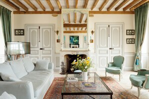 A living room with a sofa, armchairs, a coffee table, a fireplace, and a television.