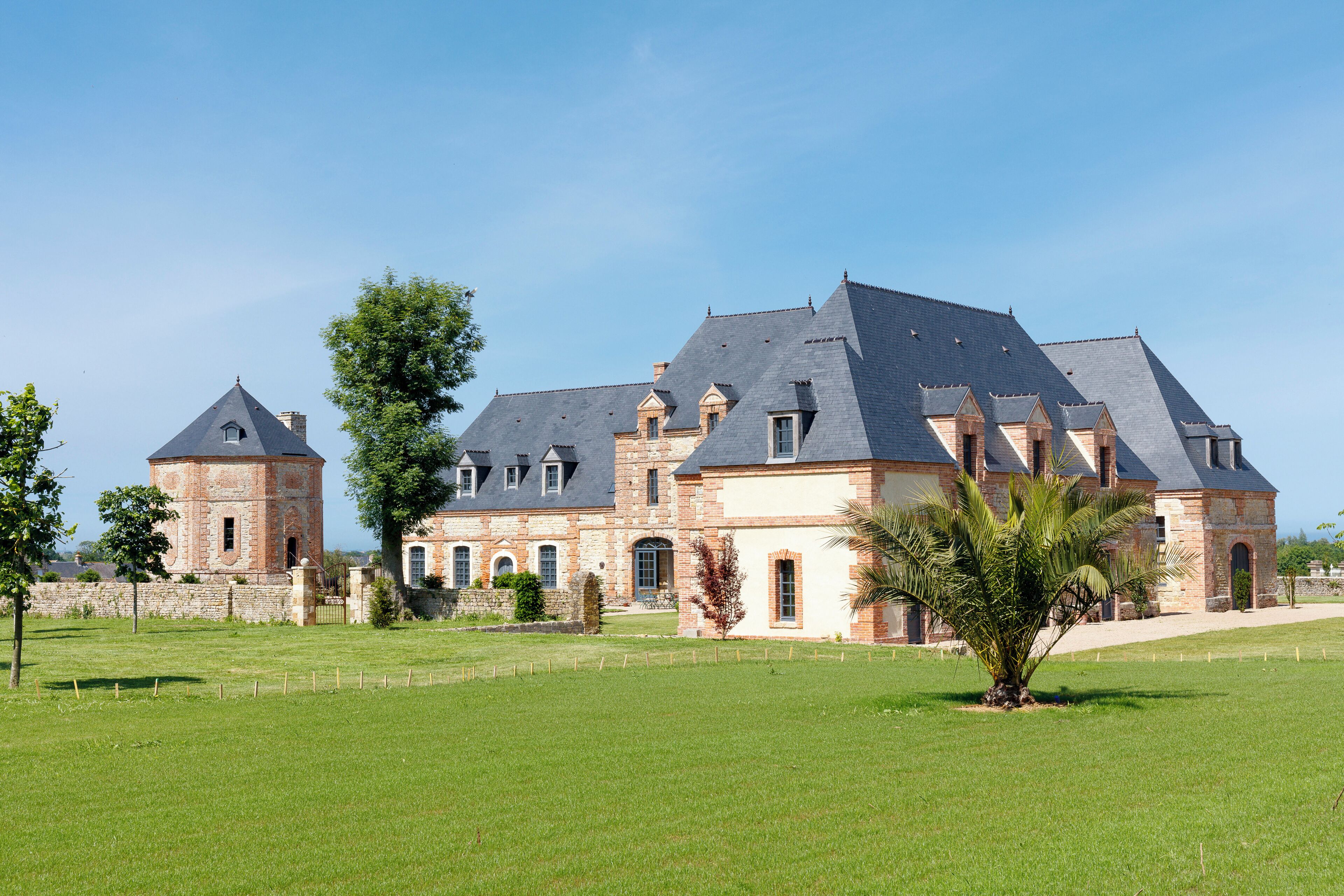 A large, historic building with multiple towers and a well-maintained lawn in front.