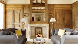 A traditional living room with two sofas, a fireplace, and wooden paneling. - Le Domaine de Ravenoville (Sainte-Mere-Eglise)